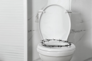 Toilet bowl with barbed wire in rest room. Hemorrhoids concept