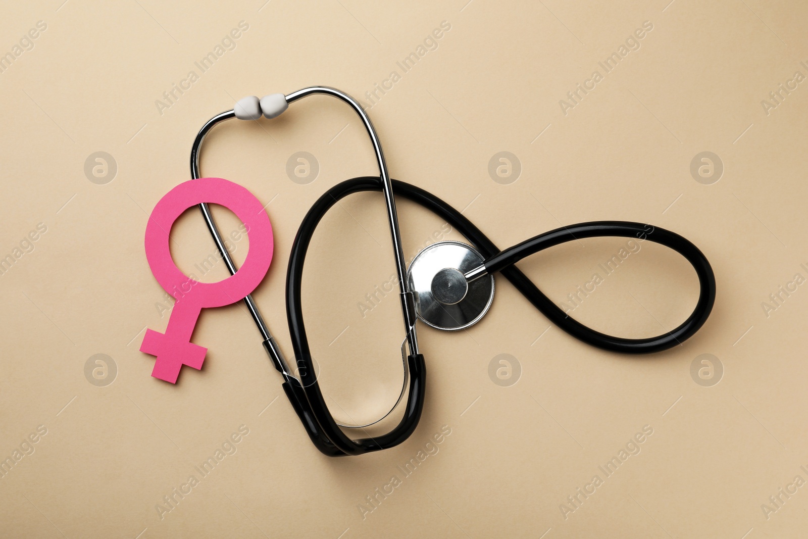 Photo of Female gender sign and stethoscope on beige background, flat lay. Women's health concept