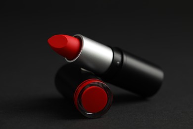 Photo of Beautiful lipstick on black background. Cosmetic product