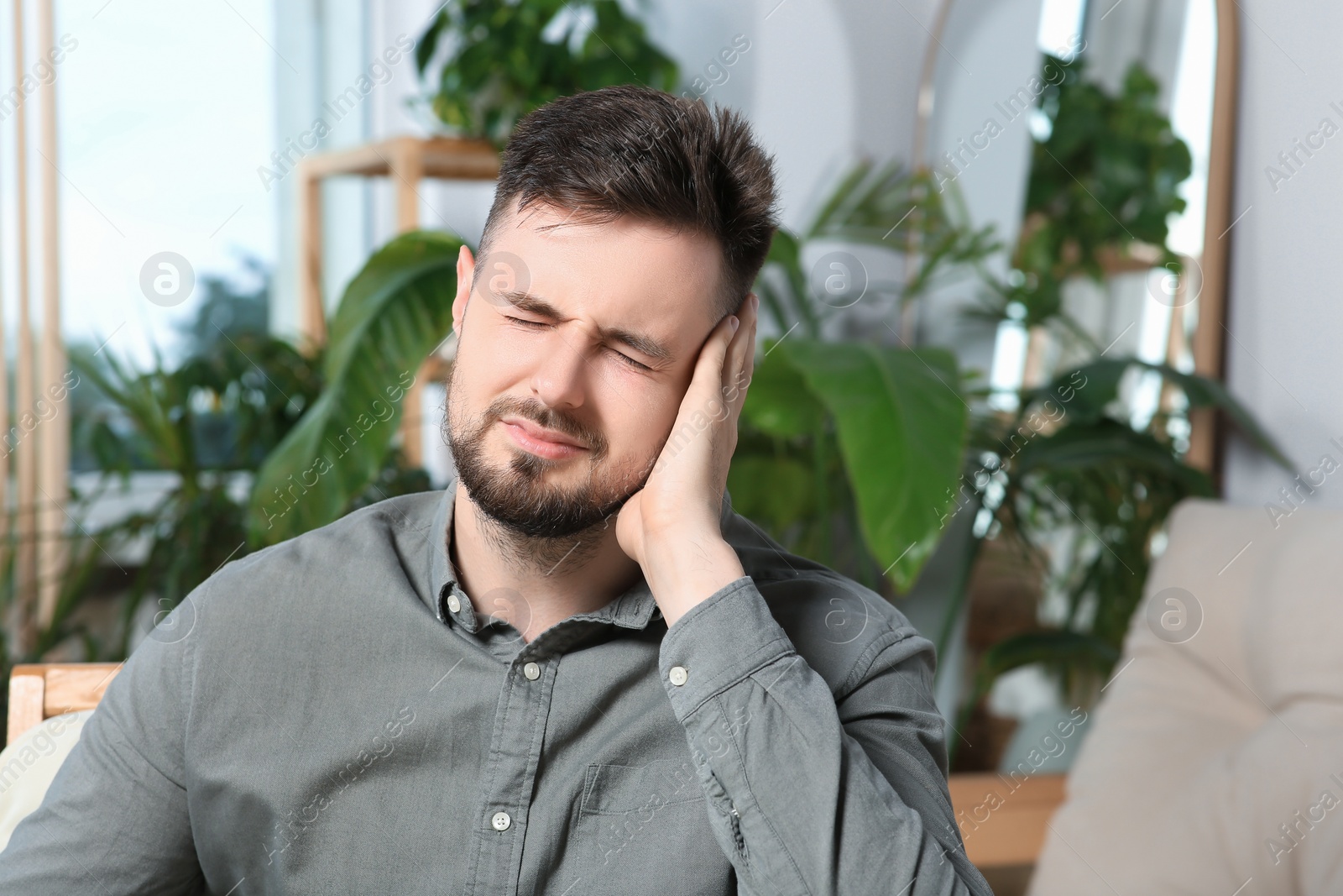 Photo of Young man suffering from ear pain at home