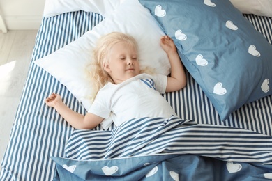 Photo of Cute little girl sleeping in bed at home, view from above