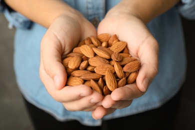 Woman holding organic almond nuts in hands, closeup