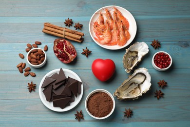 Photo of Natural aphrodisiac. Different food products and heart model on light blue wooden table, flat lay