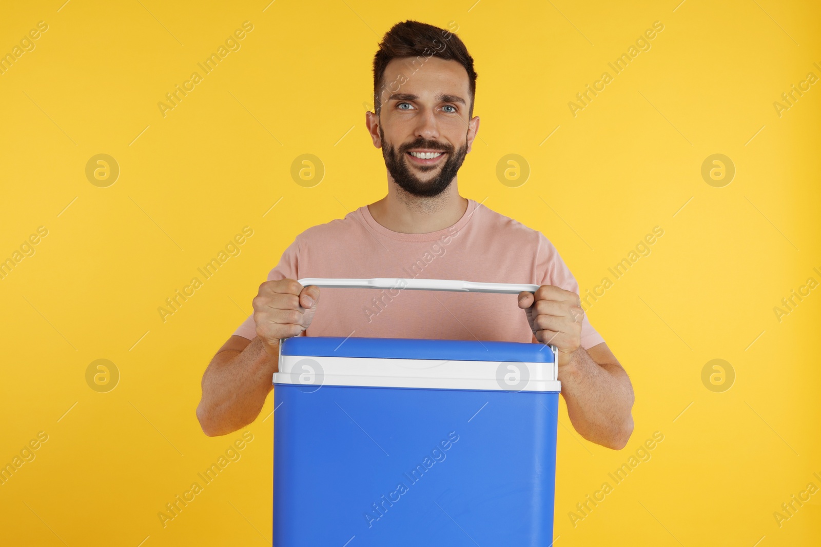 Photo of Happy man with cool box on yellow background