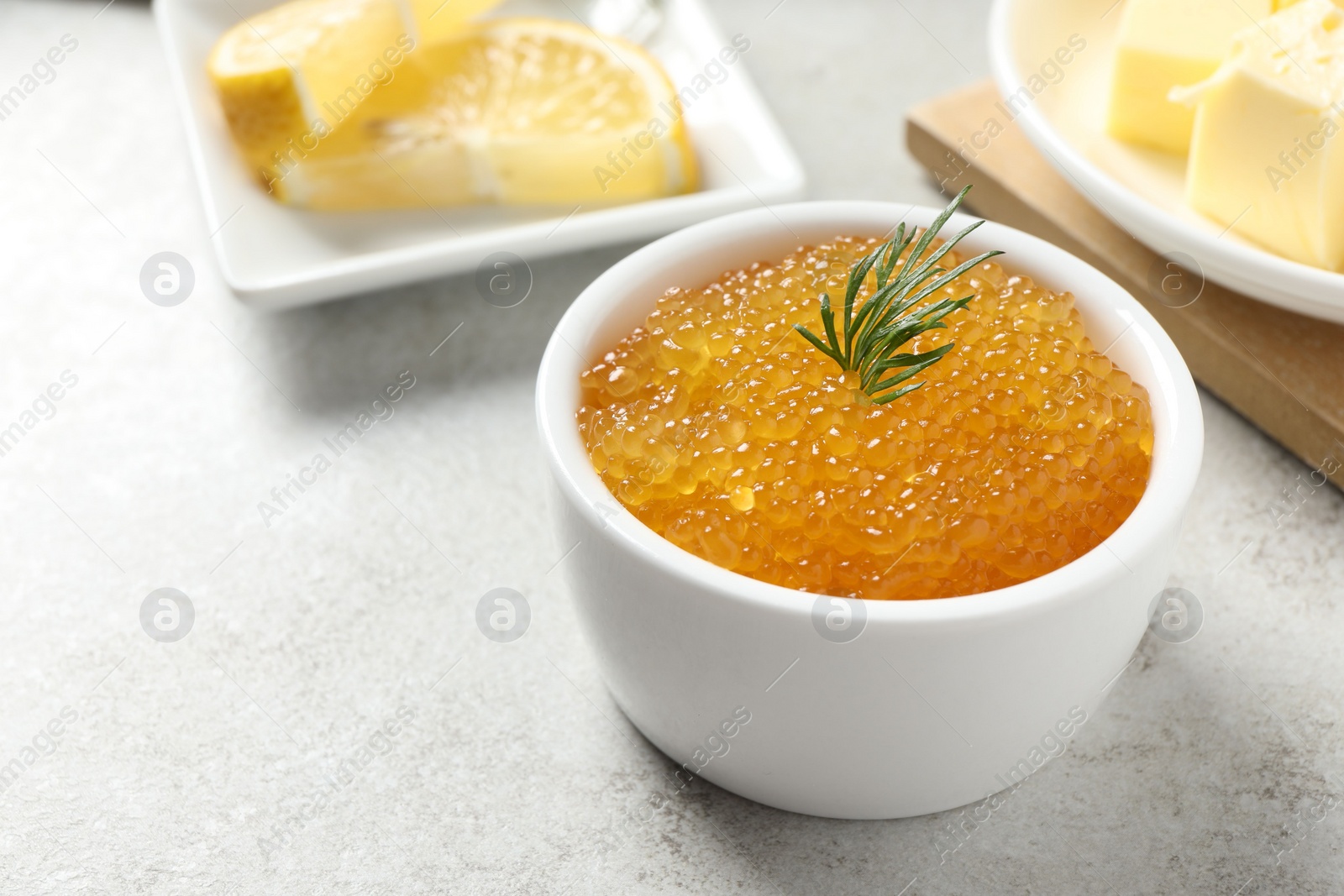 Photo of Fresh pike caviar and dill in bowl on light grey table, closeup