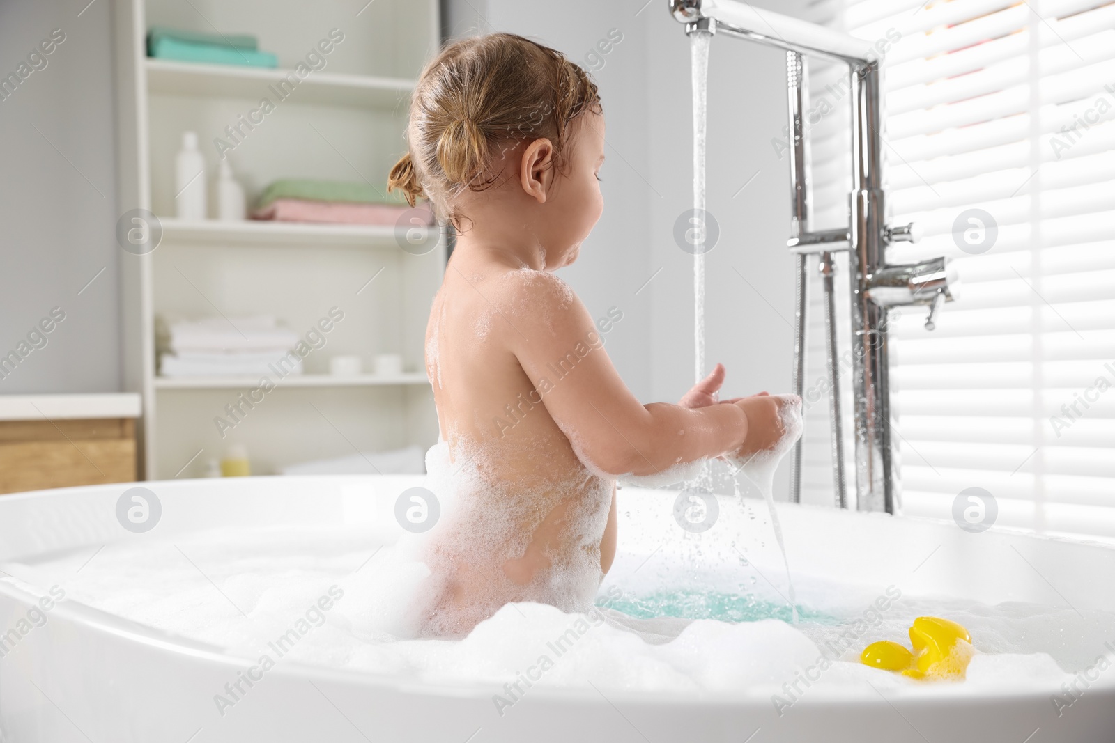 Photo of Cute little girl in foamy bath at home