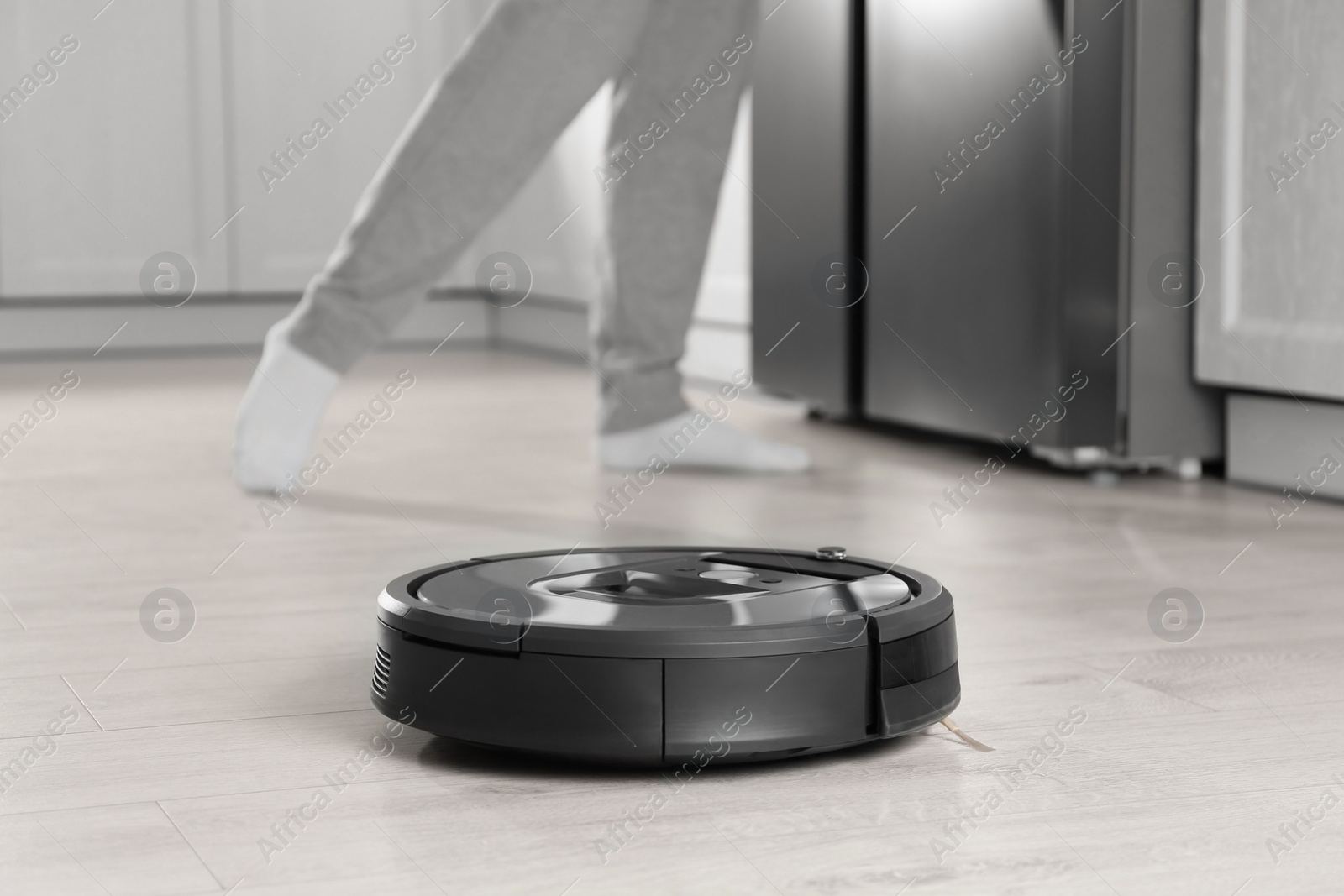 Photo of Modern robotic vacuum cleaner and blurred woman on background