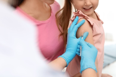 Photo of Children's doctor vaccinating little girl, closeup view