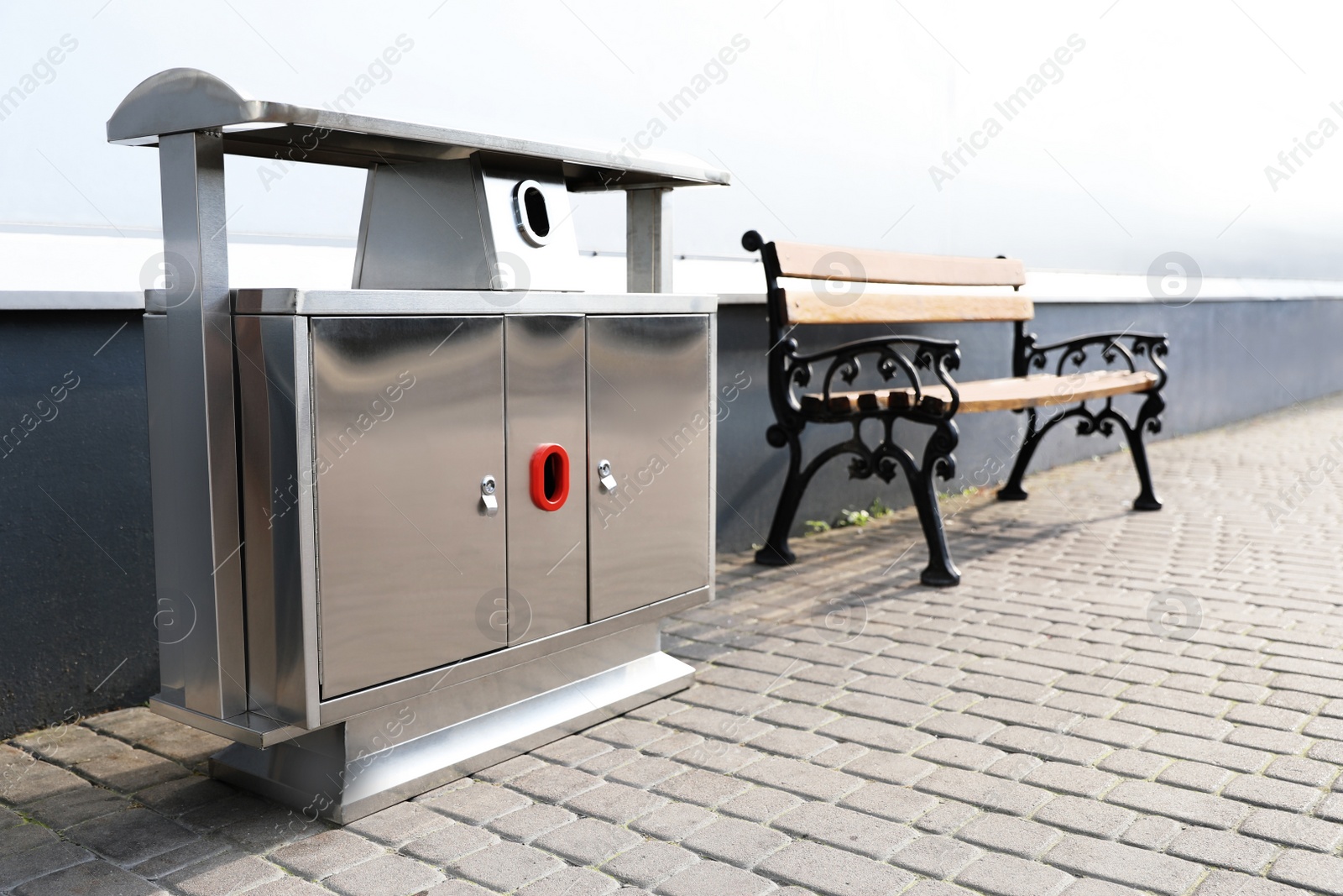 Photo of Modern metal recycling bin on street near building. Space for text