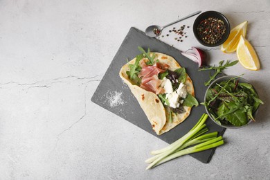 Photo of Delicious pita wrap with jamon, cheese cream and greens on light gray table, flat lay. Space for text