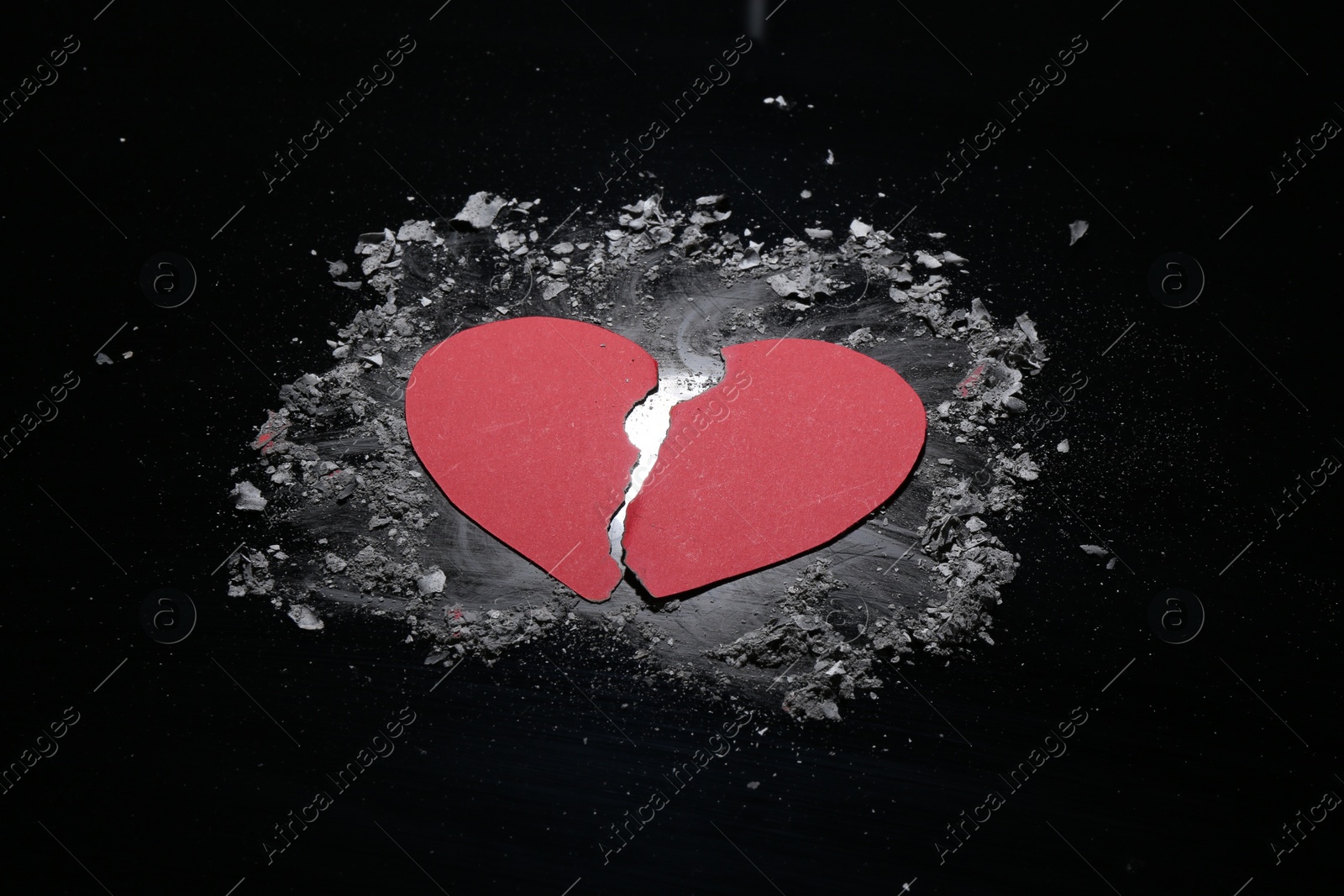 Photo of Halves of torn paper heart and ash on black background