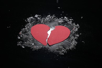 Photo of Halves of torn paper heart and ash on black background