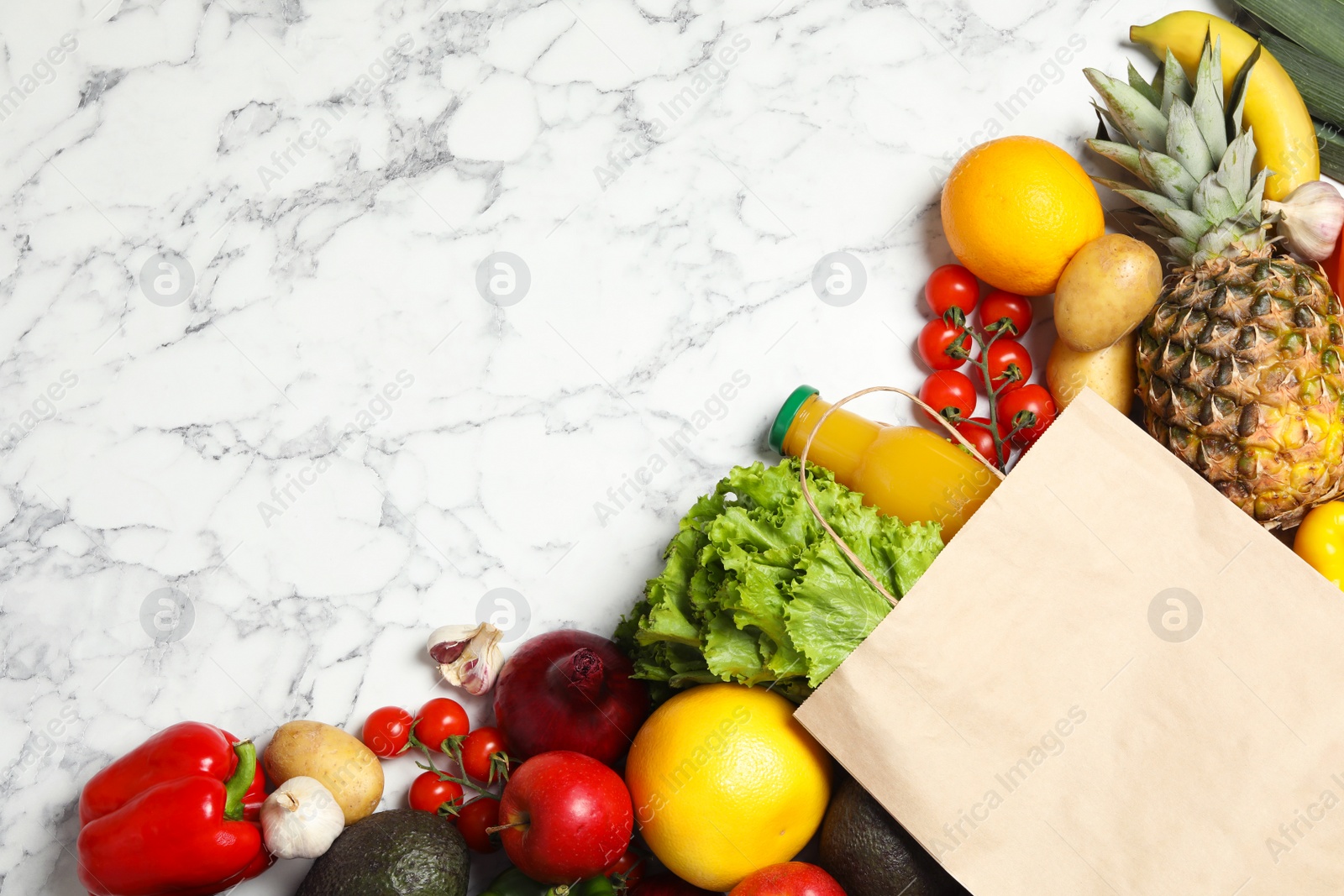 Photo of Shopping paper bag with different groceries on white marble background, flat lay. Space for text