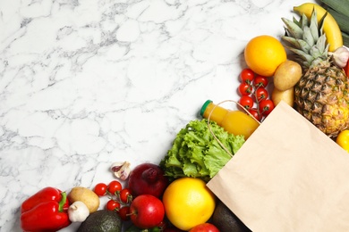 Photo of Shopping paper bag with different groceries on white marble background, flat lay. Space for text