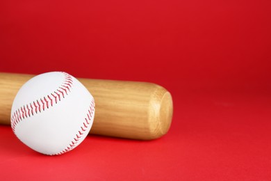 Photo of Wooden baseball bat and ball on red background, closeup. Space for text