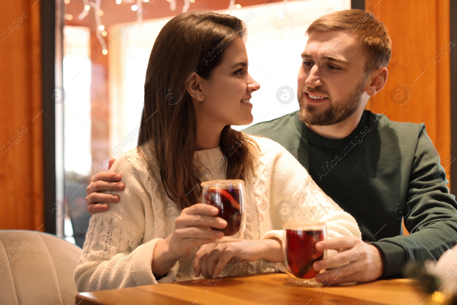 Photo of Couple with tasty mulled wine at table in cafe. Winter vacation