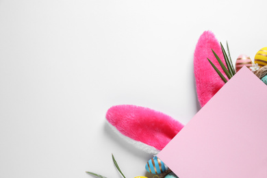 Photo of Composition with decorative bunny ears on white background, top view. Easter holiday