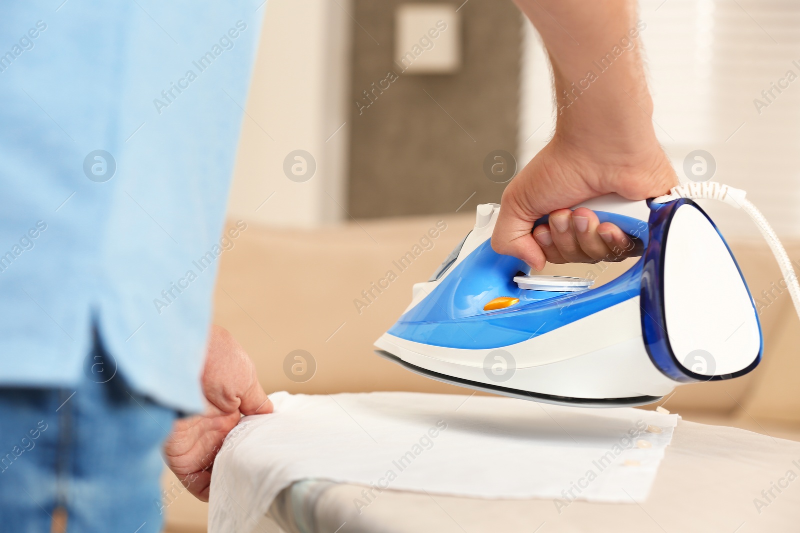 Photo of Handsome man ironing clean laundry at home, closeup