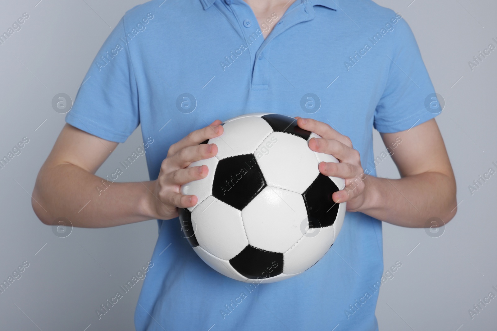 Photo of Boy with soccer ball on light grey background, closeup