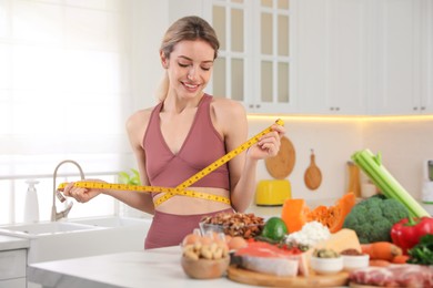 Photo of Woman with measuring tape and different products in kitchen. Keto diet