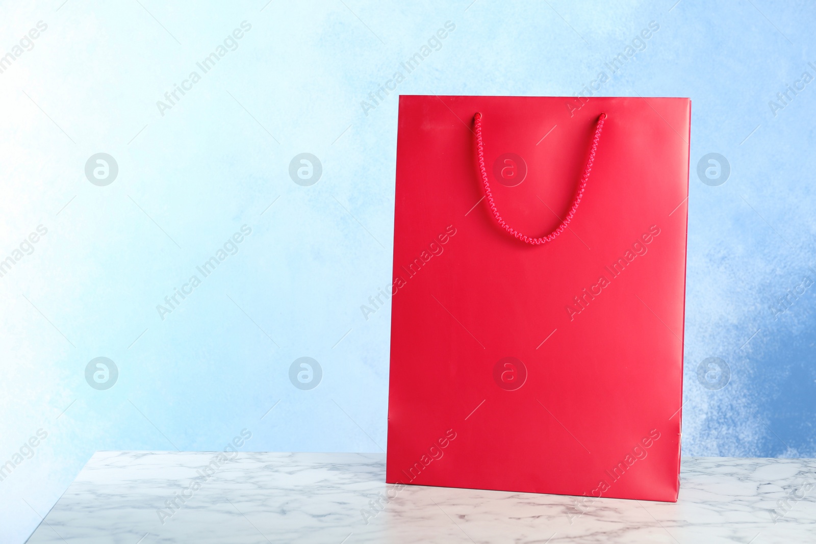 Photo of Mockup of paper shopping bag on table against color background