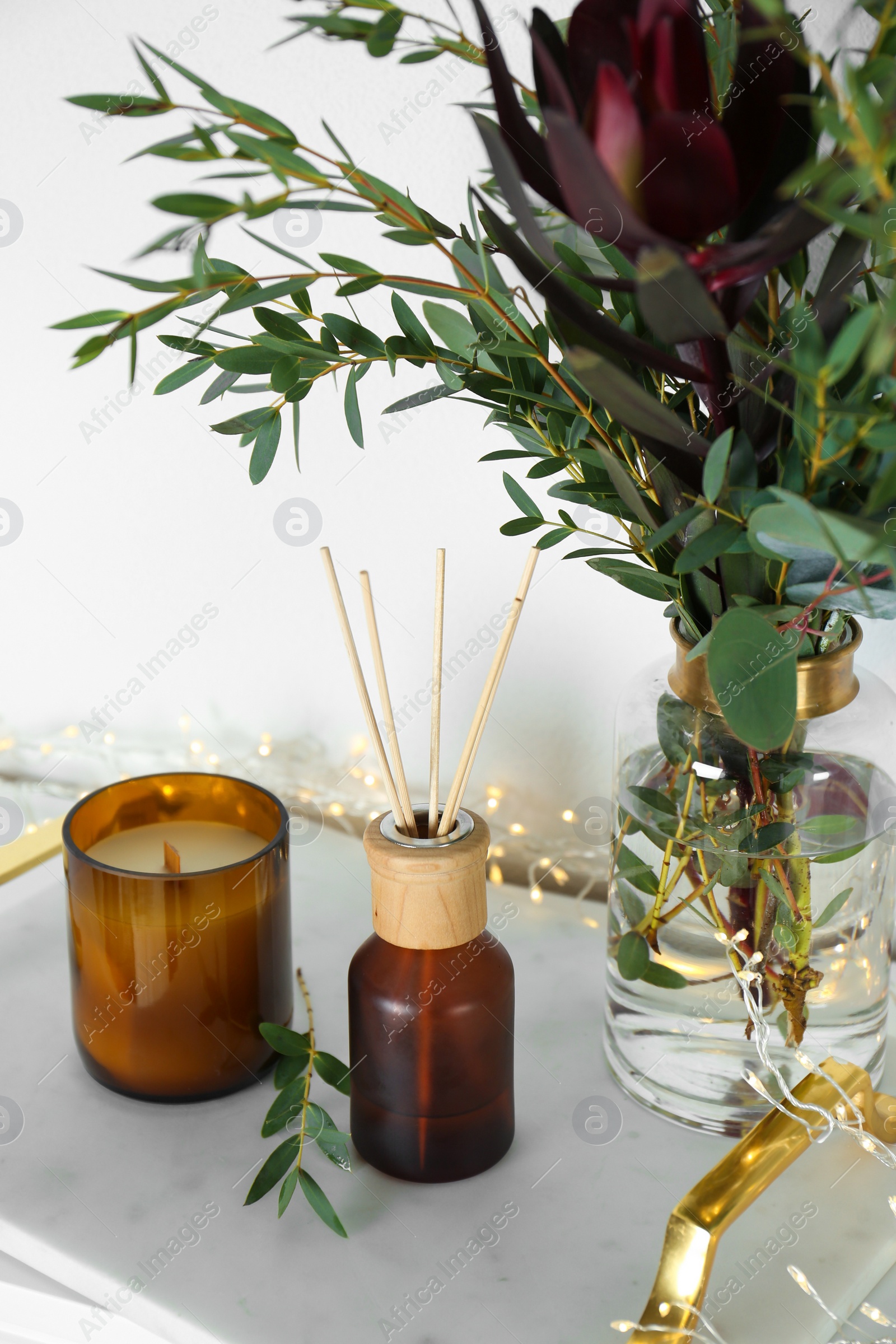 Photo of Reed air freshener with candle and bouquet on  marble tray