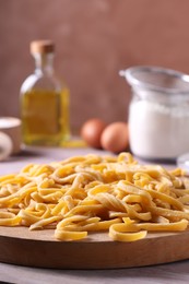 Photo of Board with homemade pasta on wooden table