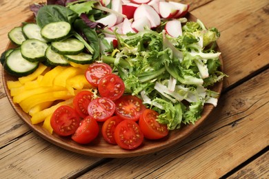 Photo of Vegetarian diet. Plate with tasty vegetables on wooden table, closeup