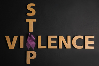 Purple ribbon and phrase STOP VIOLENCE on black background, flat lay