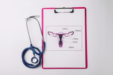 Photo of Picture of female reproductive system with stethoscope on white background, top view. Gynecological care