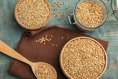 Photo of Uncooked green buckwheat grains on light blue wooden table, flat lay