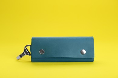 Stylish leather keys holder on yellow background