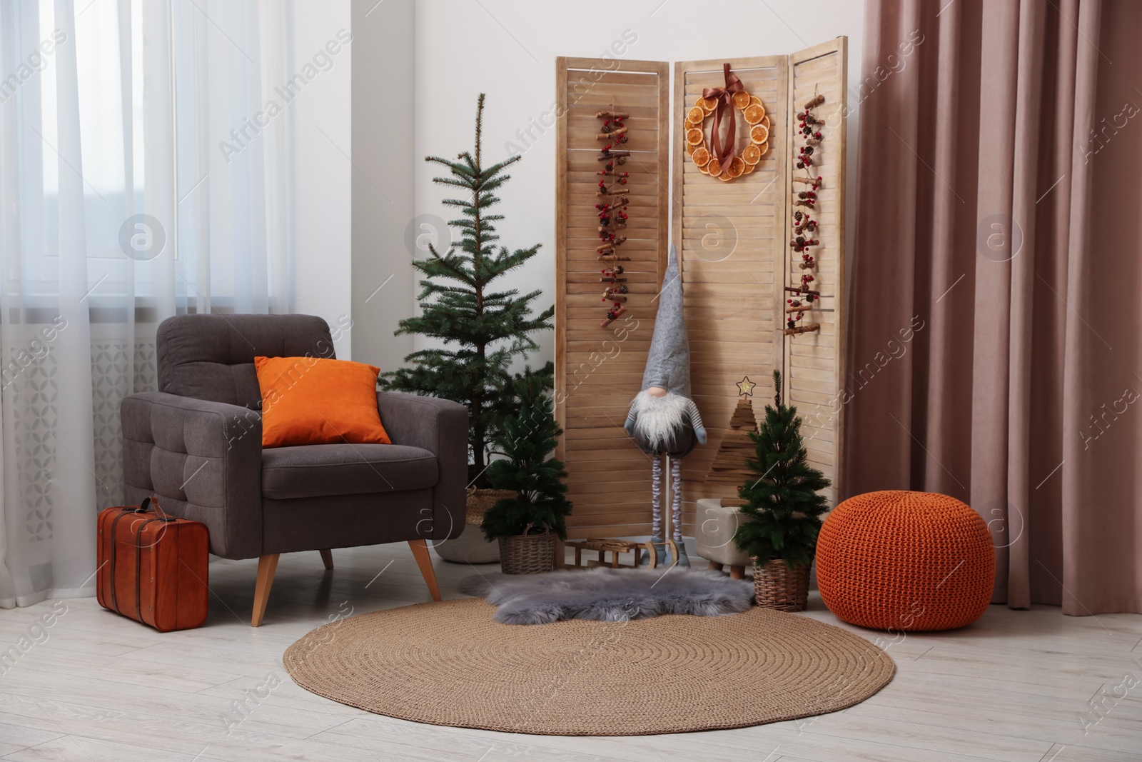 Photo of Beautiful Christmas themed photo zone with trees, dwarf and armchair in room