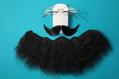 Photo of Flat lay composition with artificial moustache and glasses on light blue background