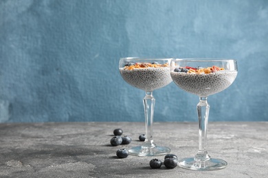 Photo of Tasty chia seed pudding with granola and blueberries on table. Space for text