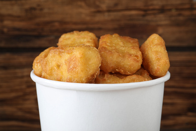 Bucket with tasty chicken nuggets on wooden background, closeup