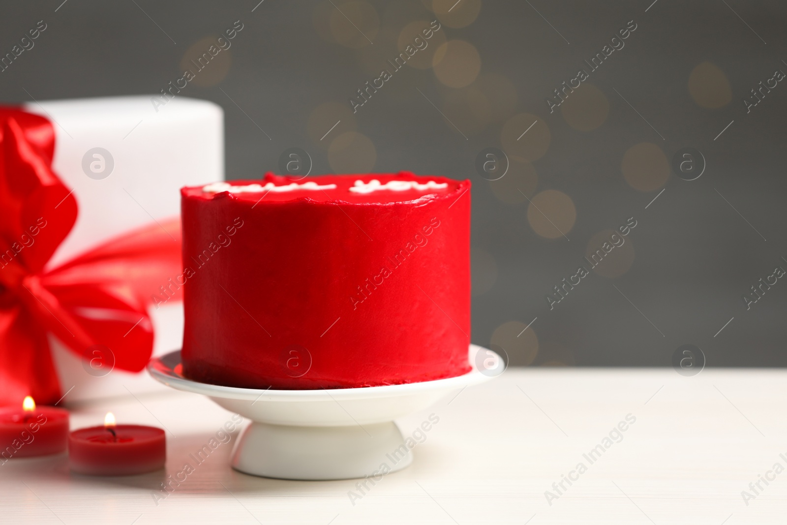 Photo of Bento cake, gift box and candles on white wooden table, space for text. St. Valentine's day surprise