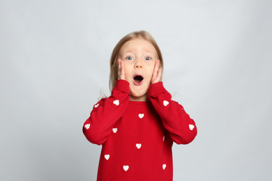 Portrait of cute emotional little girl on light grey background