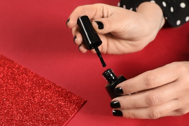 Photo of Woman opening nail polish bottle on color background, closeup. Space for text