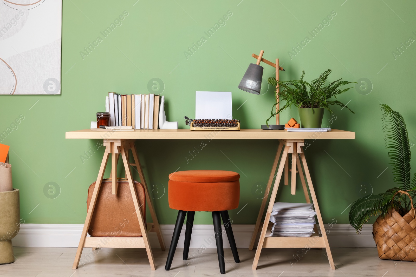 Photo of Writer's workplace with typewriter on wooden desk near pale green wall in room