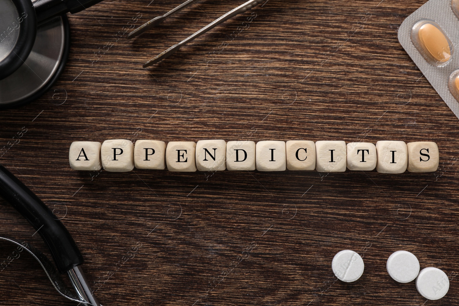 Photo of Word Appendicitis made of cubes, pills and medical supplies on wooden table, flat lay