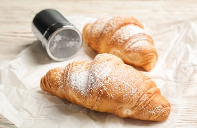 Tasty croissants with sugar powder on table