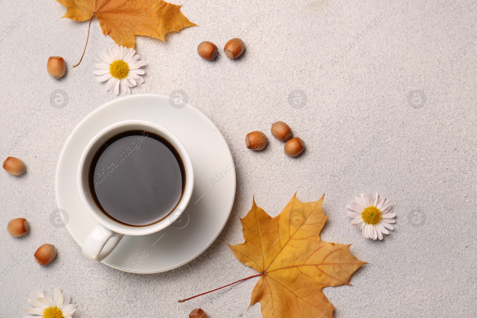 Photo of Flat lay composition with cup of hot drink and autumn leaves on light grey textured table. Space for text