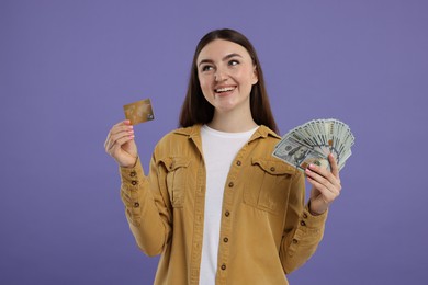 Photo of Happy woman with credit card and dollar banknotes on purple background