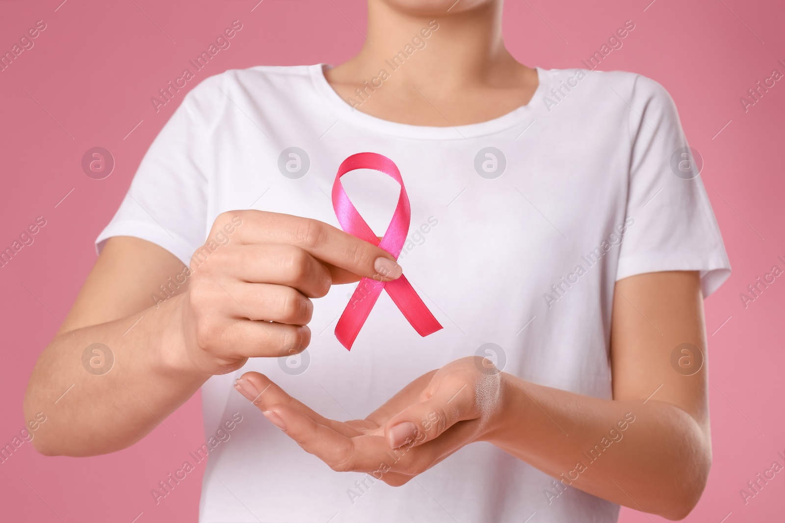 Photo of Woman holding pink ribbon on color background, closeup. Breast cancer awareness