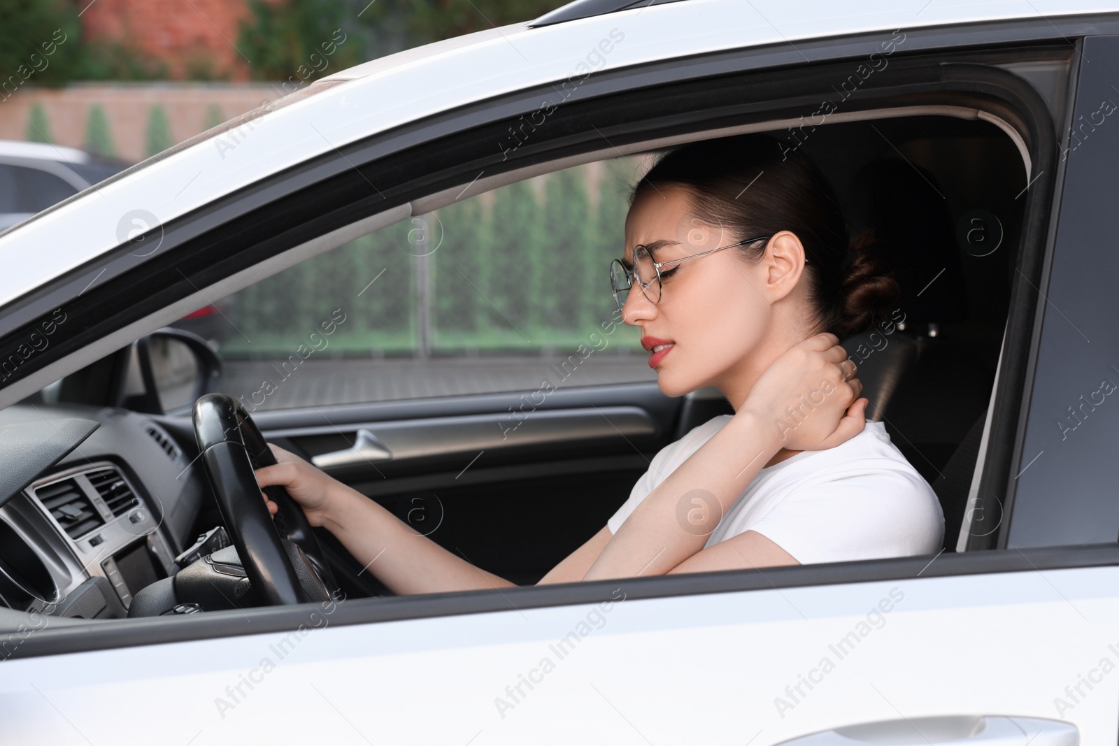 Photo of Young woman suffering from neck pain in her car