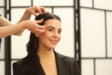 Photo of Hair styling. Professional hairdresser working with smiling client in salon, closeup. Space for text