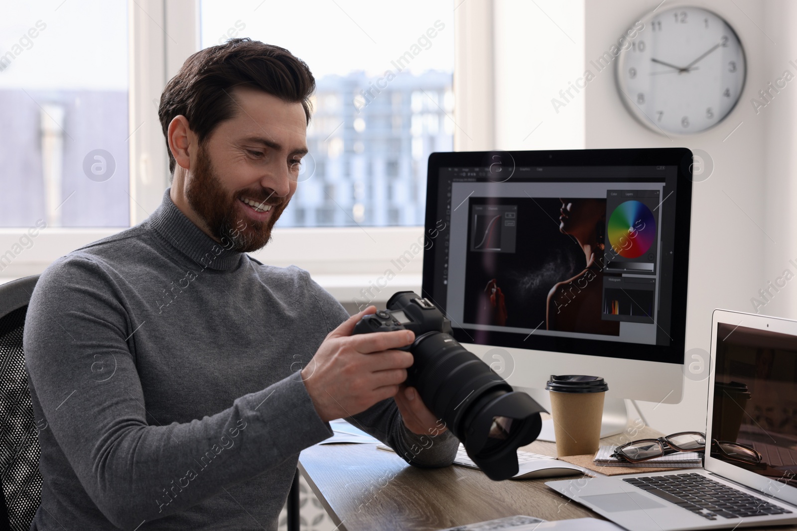 Photo of Professional photographer with digital camera at table in office