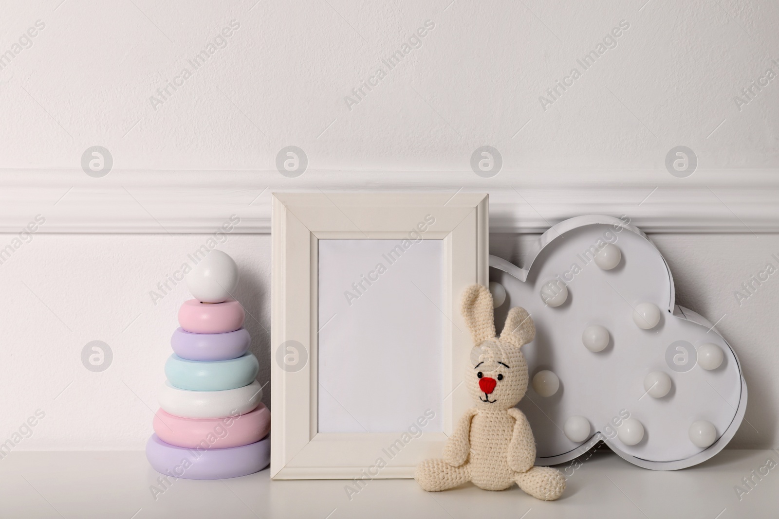 Photo of Empty photo frame, cute toys and decor near wall, space for text. Baby room interior element