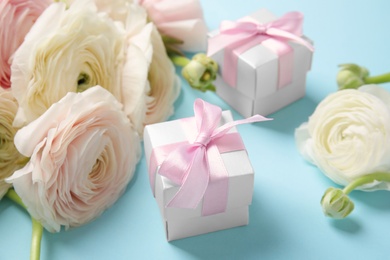 Photo of Beautiful ranunculus flowers and gift boxes on color background